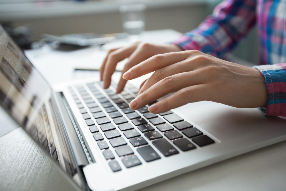 cropped-view-hands-typing-laptop